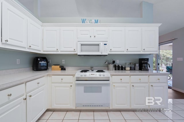 kitchen with white appliances, white cabinets, light tile patterned floors, and light countertops