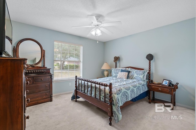 bedroom featuring baseboards, light carpet, a textured ceiling, and a ceiling fan