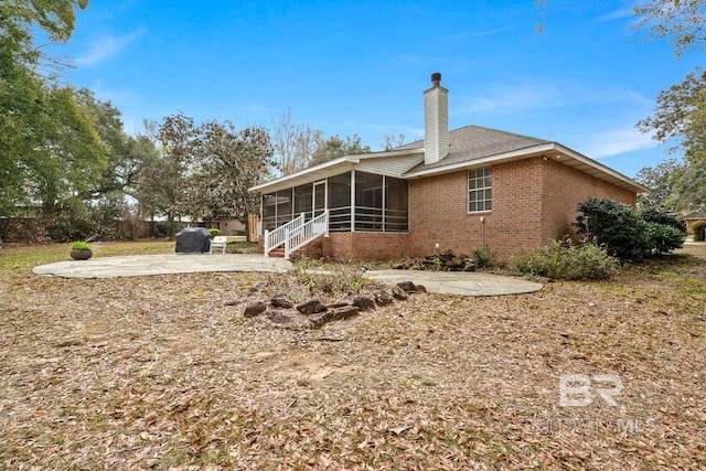 back of house featuring a patio, fence, a sunroom, brick siding, and a chimney