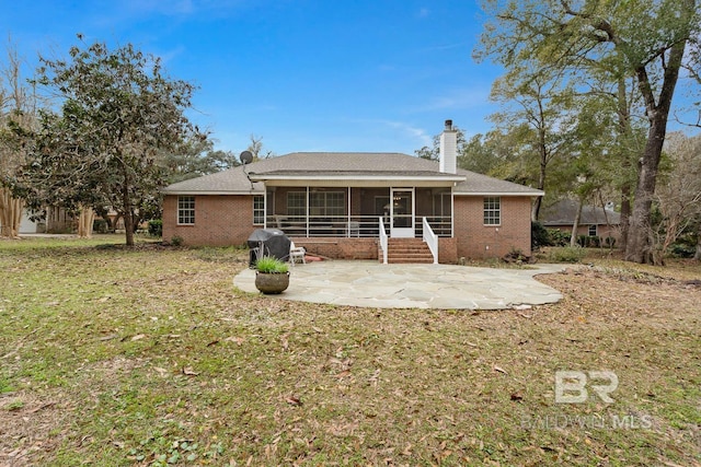 back of property featuring a patio area, brick siding, a sunroom, and a chimney