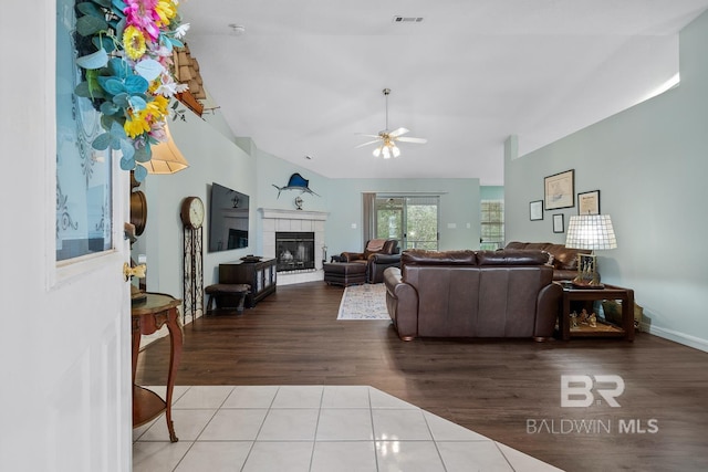 living area featuring visible vents, ceiling fan, vaulted ceiling, a fireplace, and tile patterned floors