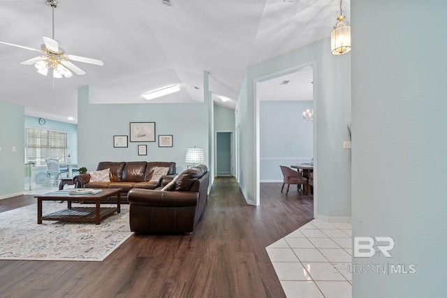 living area with baseboards, lofted ceiling, and wood finished floors