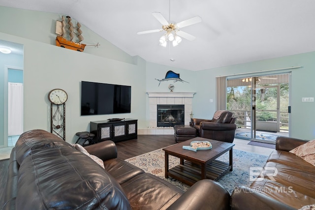 living room featuring ceiling fan, wood finished floors, vaulted ceiling, and a tile fireplace