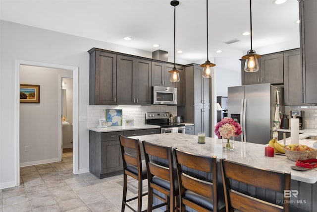 kitchen with light stone counters, pendant lighting, stainless steel appliances, visible vents, and a peninsula