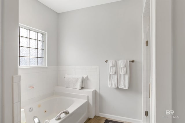 bathroom with a jetted tub and baseboards