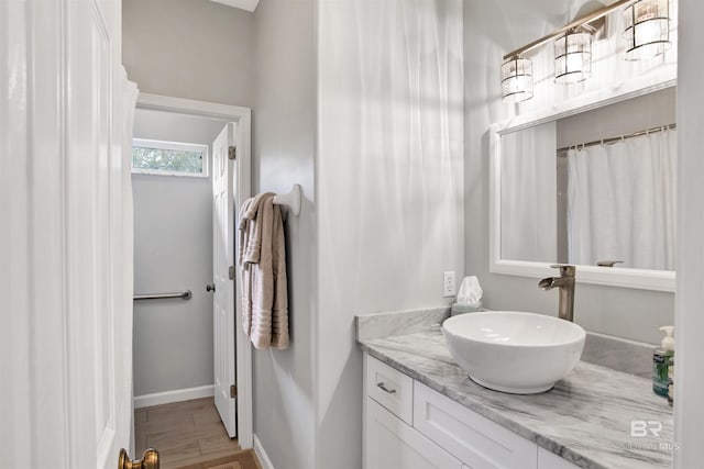 bathroom featuring baseboards, wood finished floors, and vanity