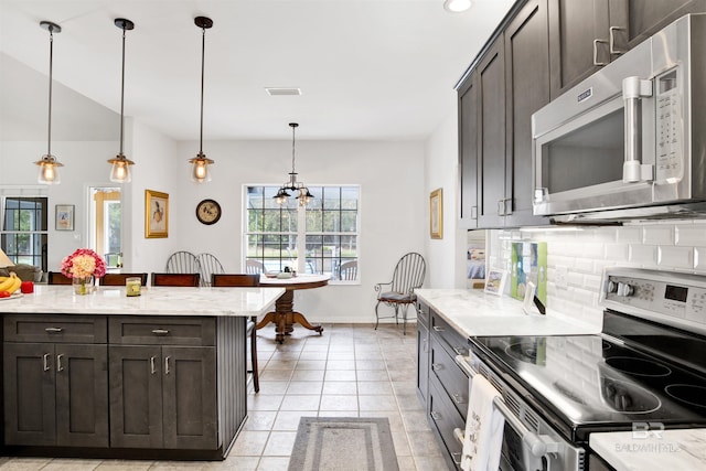 kitchen featuring light tile patterned flooring, visible vents, a kitchen breakfast bar, appliances with stainless steel finishes, and decorative backsplash