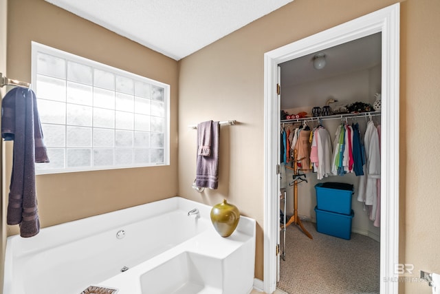 full bathroom featuring a walk in closet and a garden tub