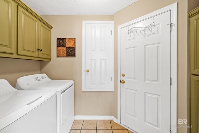 washroom featuring a textured ceiling, baseboards, cabinet space, washer and dryer, and light tile patterned floors