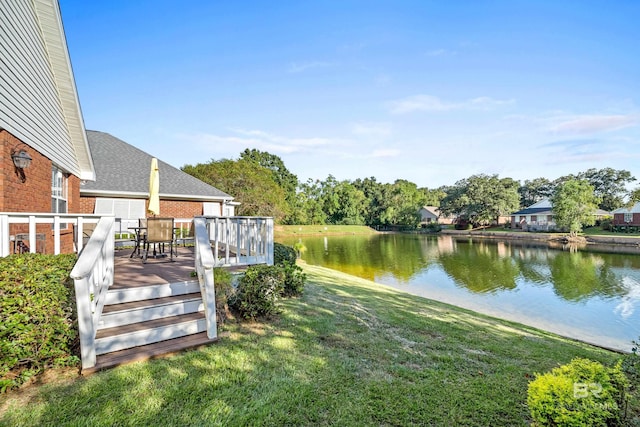 view of yard with outdoor dining area and a deck with water view