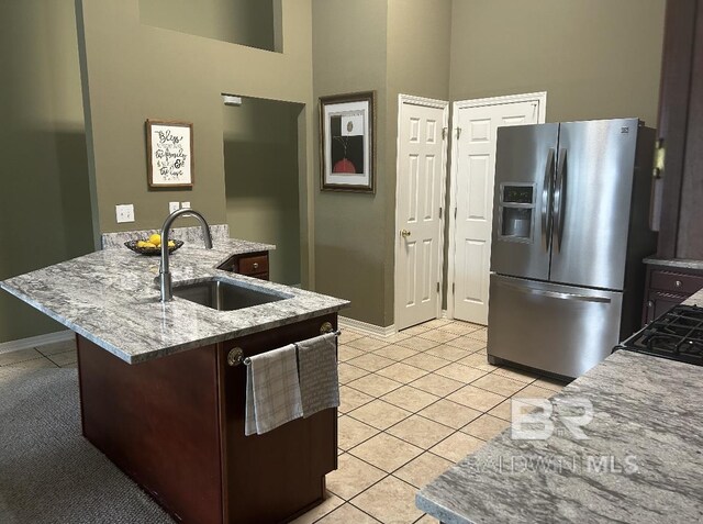 kitchen with a peninsula, light tile patterned flooring, a sink, and stainless steel fridge with ice dispenser