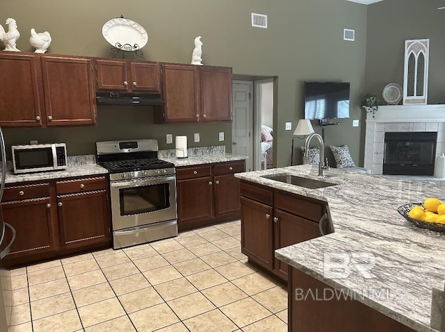 kitchen with a sink, visible vents, a towering ceiling, under cabinet range hood, and appliances with stainless steel finishes