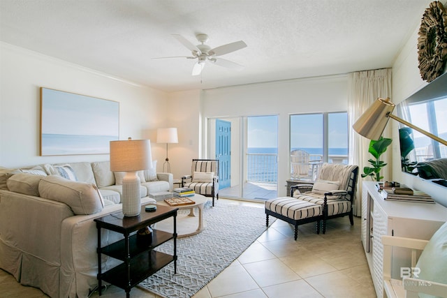 tiled living room featuring a textured ceiling, ceiling fan, ornamental molding, and a water view