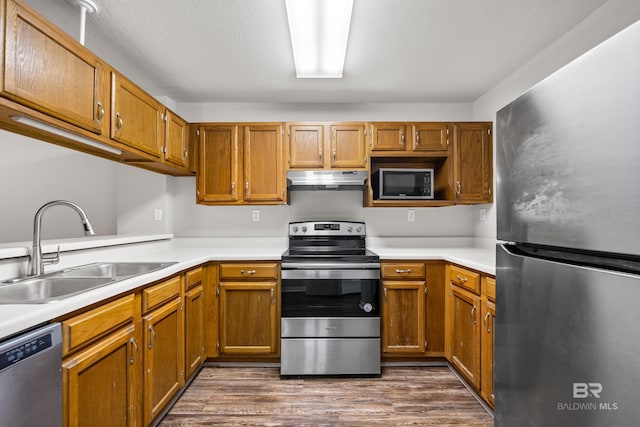 20 Summer Oaks Dr, Daphne, AL 36526 - kitchen with stainless steel appliances, under cabinet range hood, light countertops, dark wood finished floors, and brown cabinetry