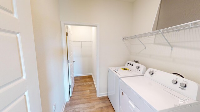 laundry room with washing machine and dryer and light wood-type flooring