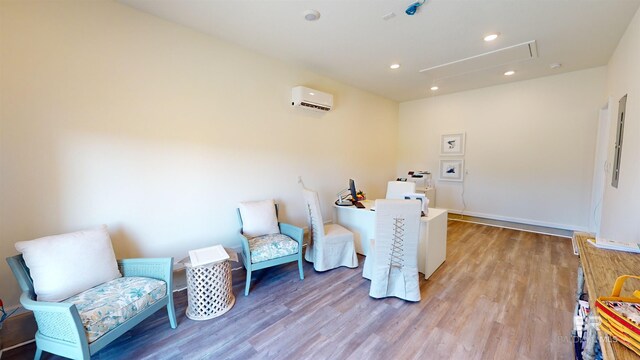 sitting room with a wall unit AC and light hardwood / wood-style floors