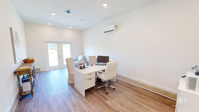 office space featuring a wall mounted air conditioner, french doors, and light hardwood / wood-style floors