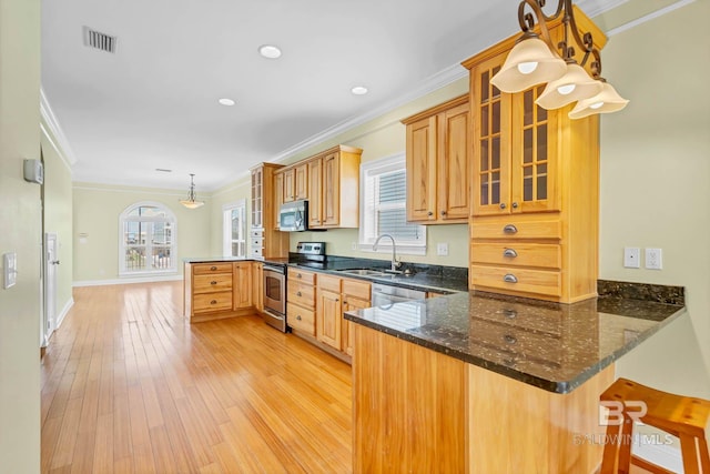 1328 W Lagoon Ave, Gulf Shores, AL 36542 - kitchen featuring stainless steel appliances, a peninsula, ornamental molding, light wood finished floors, and glass insert cabinets