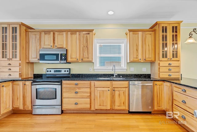 1328 W Lagoon Ave, Gulf Shores, AL 36542 - kitchen featuring appliances with stainless steel finishes, crown molding, dark stone counters, glass insert cabinets, and light wood-type flooring