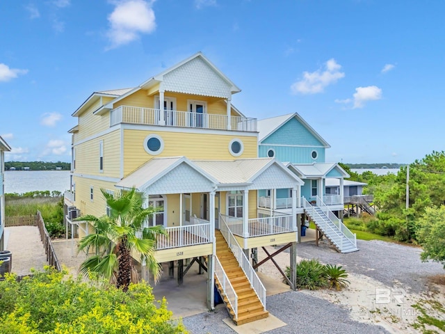 1328 W Lagoon Ave, Gulf Shores, AL 36542 - coastal inspired home with stairway, a balcony, covered porch, a carport, and a water view