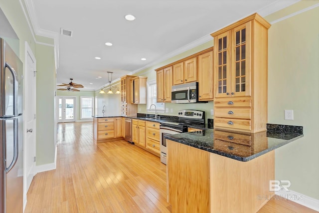 1328 W Lagoon Ave, Gulf Shores, AL 36542 - kitchen with stainless steel appliances, a peninsula, ornamental molding, a ceiling fan, and glass insert cabinets