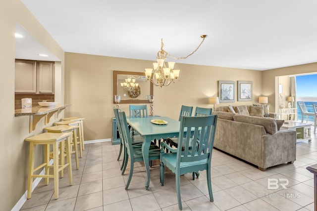 dining area with baseboards, light tile patterned flooring, and an inviting chandelier