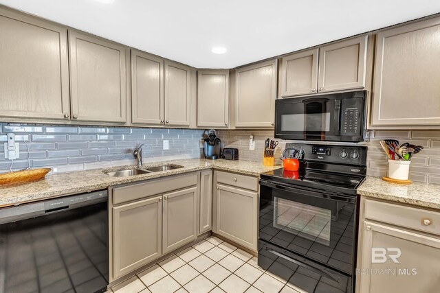 kitchen with light stone counters, a sink, black appliances, backsplash, and light tile patterned flooring