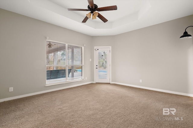 carpeted empty room featuring ceiling fan and a tray ceiling