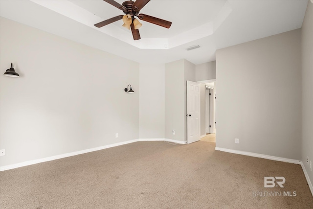 carpeted spare room featuring ceiling fan and a tray ceiling