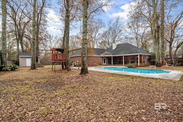 exterior space featuring a fenced in pool, a playground, and a storage unit