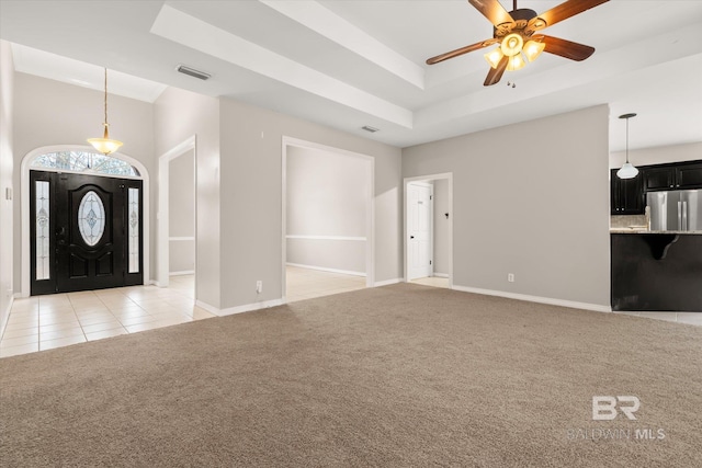 carpeted entryway featuring a towering ceiling, ceiling fan, and a tray ceiling