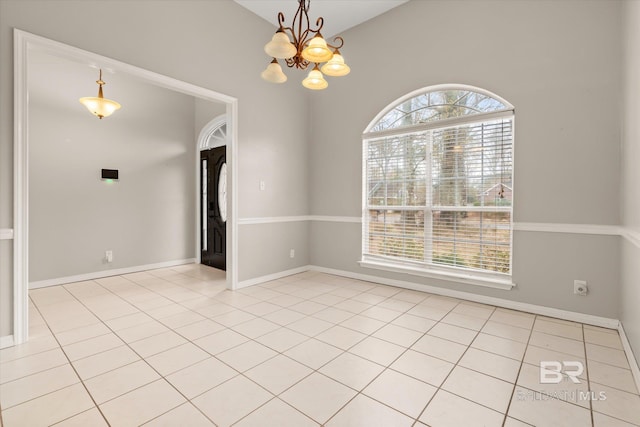 spare room with an inviting chandelier, light tile patterned floors, vaulted ceiling, and a healthy amount of sunlight