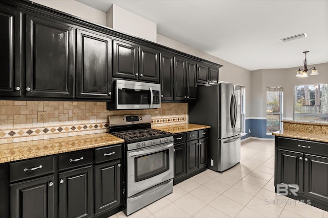 kitchen featuring pendant lighting, appliances with stainless steel finishes, backsplash, light stone countertops, and light tile patterned flooring