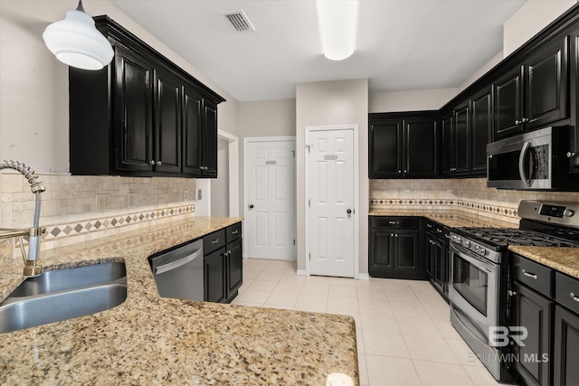 kitchen featuring sink, light tile patterned floors, hanging light fixtures, stainless steel appliances, and light stone countertops