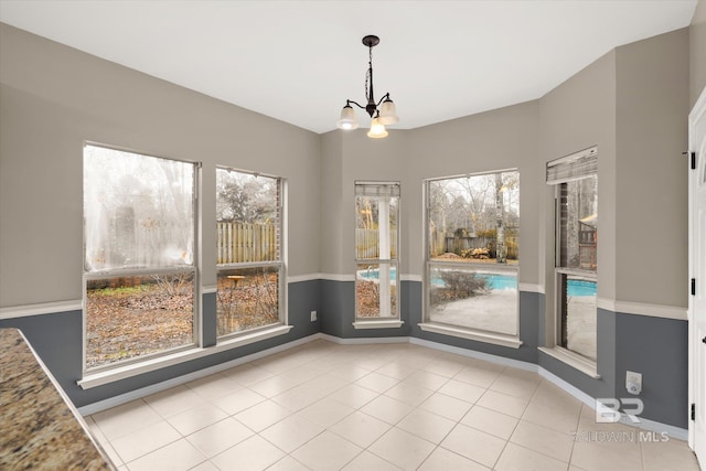 unfurnished dining area featuring an inviting chandelier, light tile patterned floors, and plenty of natural light