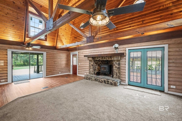 unfurnished living room with ceiling fan, rustic walls, high vaulted ceiling, and carpet