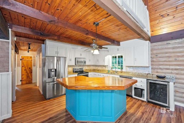 kitchen with wooden counters, a center island, appliances with stainless steel finishes, beverage cooler, and white cabinets