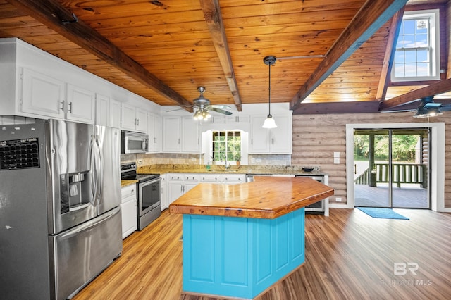 kitchen featuring wooden counters, stainless steel appliances, a center island, white cabinets, and decorative light fixtures