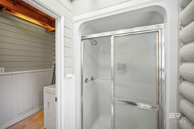 bathroom featuring washer / clothes dryer, wood-type flooring, and a shower with door
