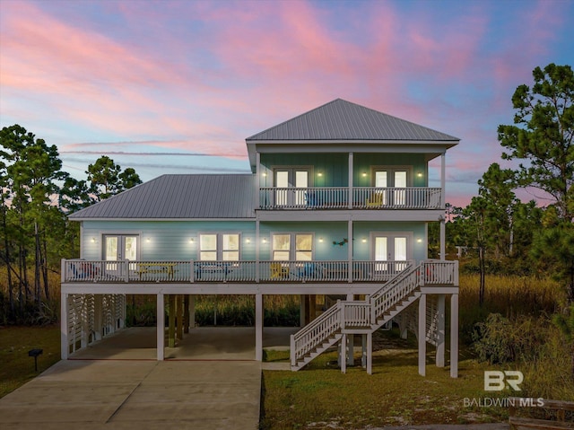 view of front of home with driveway, a balcony, stairs, french doors, and a carport