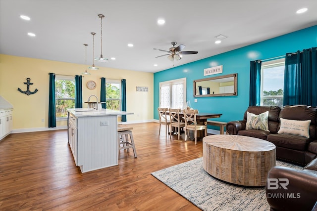 living area featuring baseboards, visible vents, wood finished floors, and recessed lighting