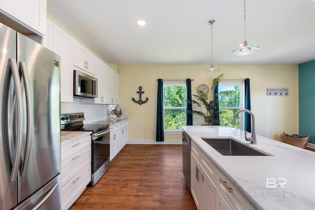 kitchen featuring dark wood-style flooring, stainless steel appliances, backsplash, white cabinets, and a sink