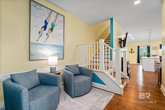 sitting room with recessed lighting, wood finished floors, baseboards, and stairs