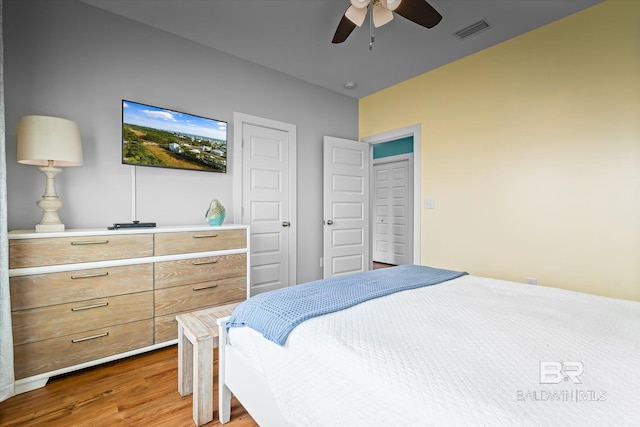 bedroom featuring a ceiling fan, visible vents, and wood finished floors