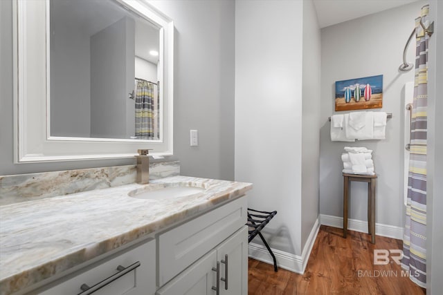 bathroom with baseboards, wood finished floors, and vanity