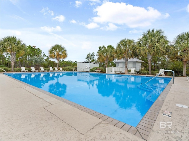 pool with a patio area and an outdoor structure