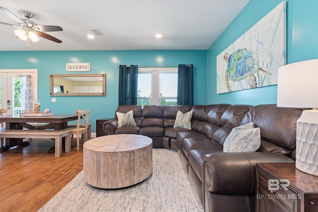 living room featuring a wealth of natural light, visible vents, ceiling fan, and wood finished floors