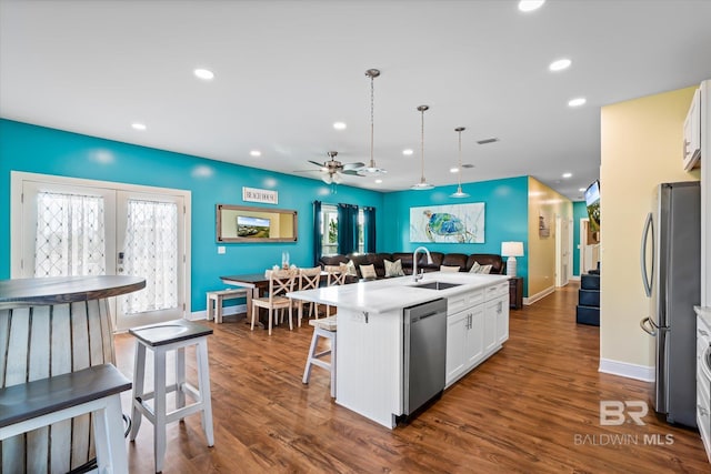 kitchen with open floor plan, stainless steel appliances, white cabinetry, a sink, and recessed lighting