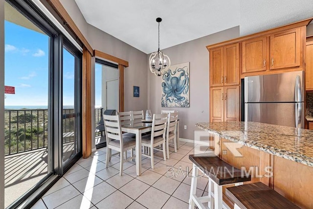 tiled dining space featuring a water view and a chandelier