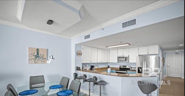 375 Beach Club Trl Unit A1704, Gulf Shores, AL 36542 - kitchen featuring stainless steel appliances, ornamental molding, a peninsula, white cabinets, and a breakfast bar area